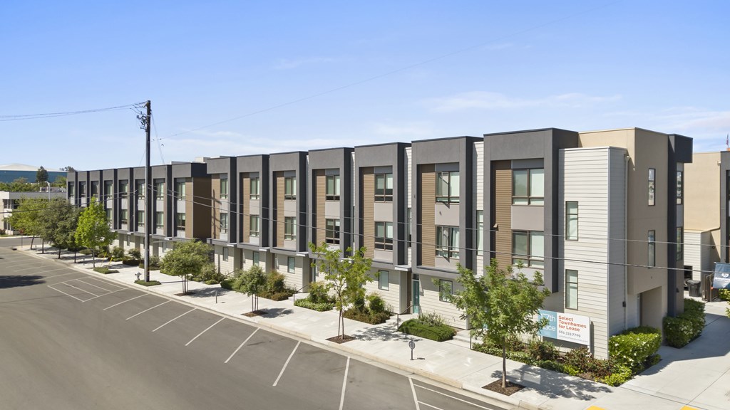 A row of modern townhouses with a clear blue sky above.